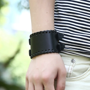 Close-up of men's wide black leather wristband with woven edges and metal buckles