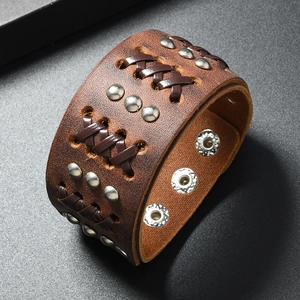 Close-up of wide punk leather bracelet with rivet studs and woven leather details