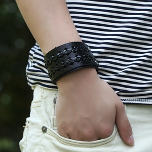 Vintage braided black leather bracelet with metal studs on male wrist in outdoor setting
