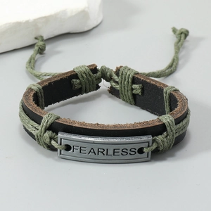 Detailed shot of braided leather bracelet featuring FEARLESS engraved metal plate