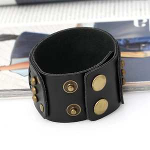 Macro detail of black vintage leather wristband with bronze rivets and snap closure