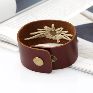 Détail d'un bracelet en cuir brun-rouge avec boutons-pression en laiton et décor de corde