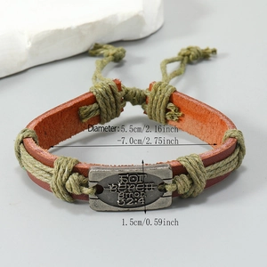 Detail of adjustable woven leather bracelet with engraved vintage metal plate and cord
