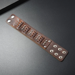 Detail of brown leather cuff with silver rivets, woven strips and adjustable snap buttons
