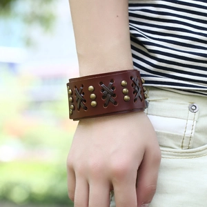 Retro punk style wide brown leather bracelet featuring copper studs and woven cross details