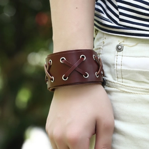 Retro punk brown braided leather bracelet with metal eyelets worn outdoors by a model