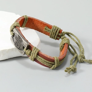 Detail of vintage braided leather bracelet with olive cord and engraved metal plate
