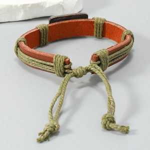 Close-up of vintage handmade braided brown leather bracelet with green cord detail