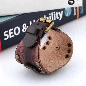 Detail of vintage punk wide leather bracelet with bronze rivets and buckle closure