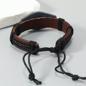 Détail d'un bracelet en cuir marron tressé à la main avec cordon ajustable et breloque métal