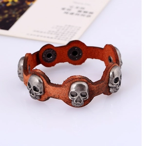 Detail eines Vintage-Lederarmbands mit fünf silbernen Totenköpfen und Metalldruckknöpfen
