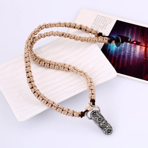 Boho vintage braided rope necklace with ethnic metal pendant on a white ceramic plate