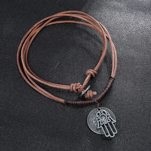Vintage braided brown leather necklace with hamsa hand charm on a dark background