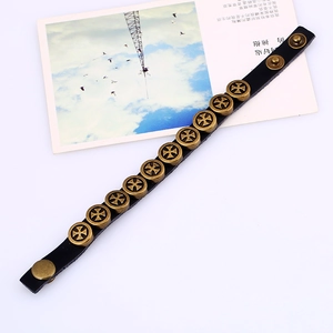 Detail view of black punk leather bracelet with ten bronze cross rivets and metal snap buttons