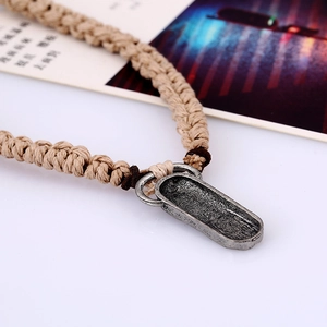 Retro braided leather necklace featuring a vintage oval metal pendant for men on white backdrop
