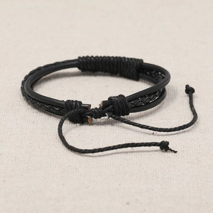 Bracelet rétro en cuir tressé noir avec cordon réglable sur un fond en lin naturel