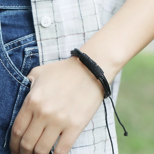 Gros plan du bracelet en cuir tressé noir avec cordon réglable sur le poignet