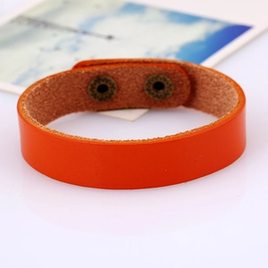 Macro detail of orange leather bracelet featuring two vintage bronze snap buttons