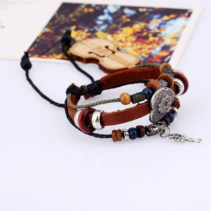 Retro multi-layer leather bracelet with wooden beads and key pendant on wooden background