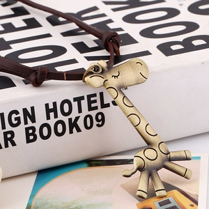 Vintage giraffe pendant on brown leather cord necklace styled on a white book
