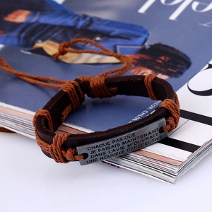 Retro braided leather bracelet with engraved vintage metal plate on a magazine background