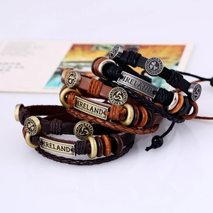 Dettaglio di bracciali in pelle intrecciata con ciondoli a trifoglio e incisione Irlanda