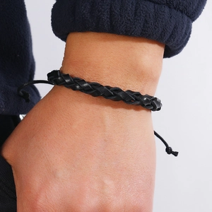 Close-up of black braided leather bracelet with adjustable drawstring on a wrist