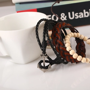 Retro multi-layer leather bracelet set with anchor charm and wooden beads on a white cup