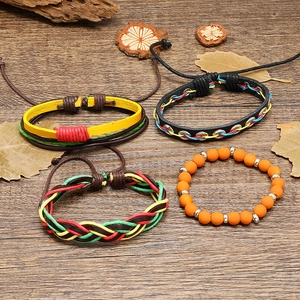 Detail von vier handgefertigten Boho-Armbändern aus Leder und Webstoff auf Holzgrund