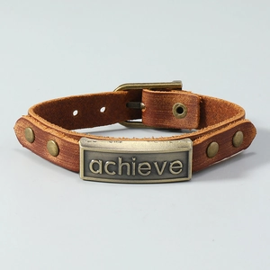 Detail of vintage brown leather bracelet featuring a bronze metal plate with achieve engraving