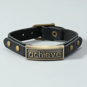 Detail of black multilayer leather bracelet with bronze 'achieve' engraved plaque and buckle