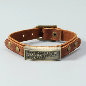 Macro shot of brown leather bracelet with bronze metal plate and engraved love quote