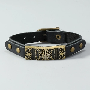 Detail of vintage punk leather bracelet featuring bronze floral plate and buckle