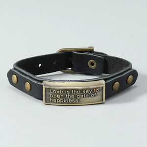 Detail of vintage leather bracelet with engraved bronze plate and adjustable buckle