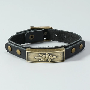 Close-up of vintage black leather bracelet featuring bronze maple leaf metal plate and rivets