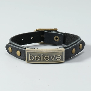 Detail view of adjustable black leather bracelet with bronze 'Believe' plaque and pin buckle