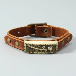 Detailed macro of vintage brown leather bracelet with rose embossed metal plate and studs