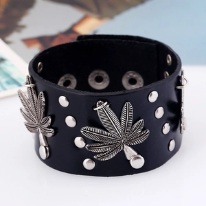 Macro detail of black leather punk bracelet featuring silver rivets and maple leaf charm