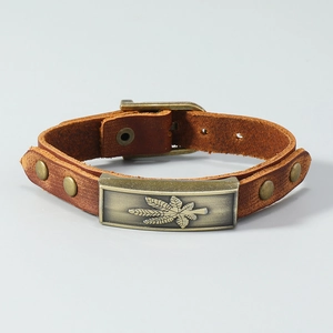Macro detail of men's brown leather bracelet with bronze leaf plaque and metal rivets