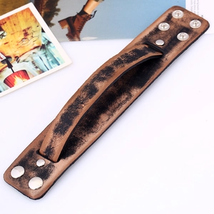 Détail d'un bracelet en cuir marron vintage avec finition vieillie et bouton pression argenté