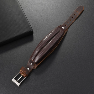 Detail of adjustable wide brown leather cuff bracelet with steel buckle and rivets