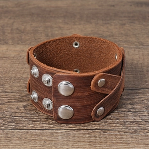 Vintage wide brown multi-layer leather bracelet with silver snap buttons on wood surface