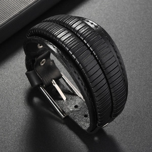 Detail of wide black leather men's bracelet with ribbed texture and silver buckle