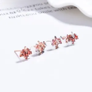 Macro shot of maple leaf stud earrings with ruby-red stones in silver and rose gold