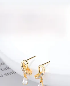 Macro detail of gold S925 sterling silver cross stud earrings with pear-cut cubic zirconia