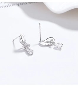 Macro detail of 925 sterling silver ribbon earrings with pavé zircons and pear drops
