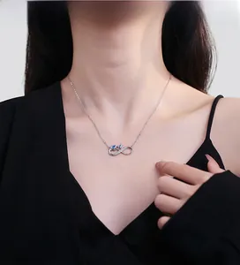 Detail of 925 sterling silver infinity cat necklace with a blue gemstone on a model