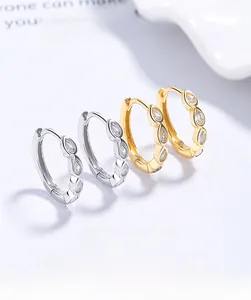 Dettaglio di orecchini a cerchio in argento 925 con zirconi a goccia in oro e argento