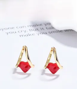 Close-up of S925 sterling silver stamp on golden earrings with red enamel hearts