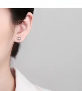 Macro detail of silver heart stud earring with starburst zircon on model ear